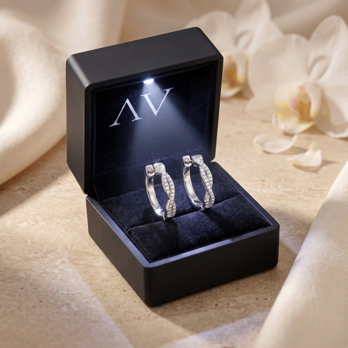 Silver moissanite twisted hoop earrings in a black LED-lit gift box.