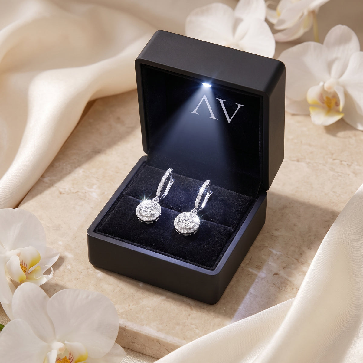 Silver moissanite drop earrings in a black LED-lit presentation box.
