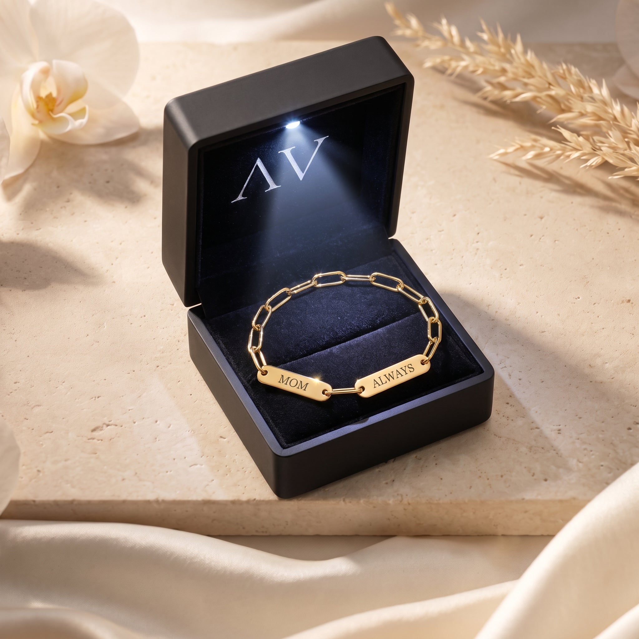 Gold personalized link bracelet with engraved name plates inside a black LED-lit gift box.