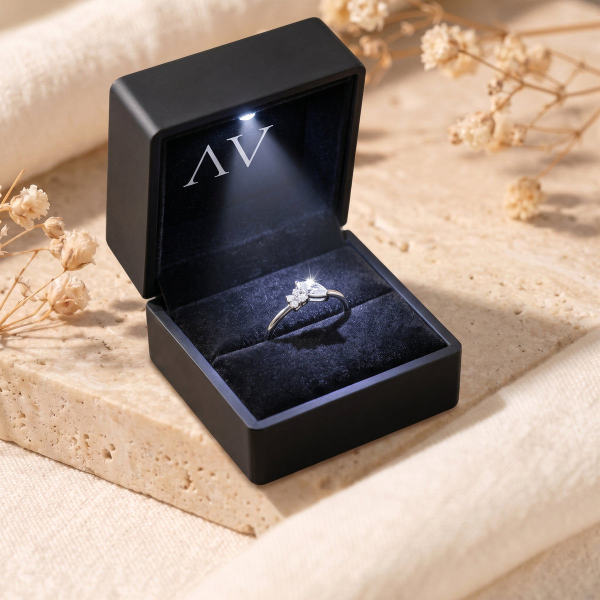 Silver marquise moissanite ring in an illuminated black gift box.