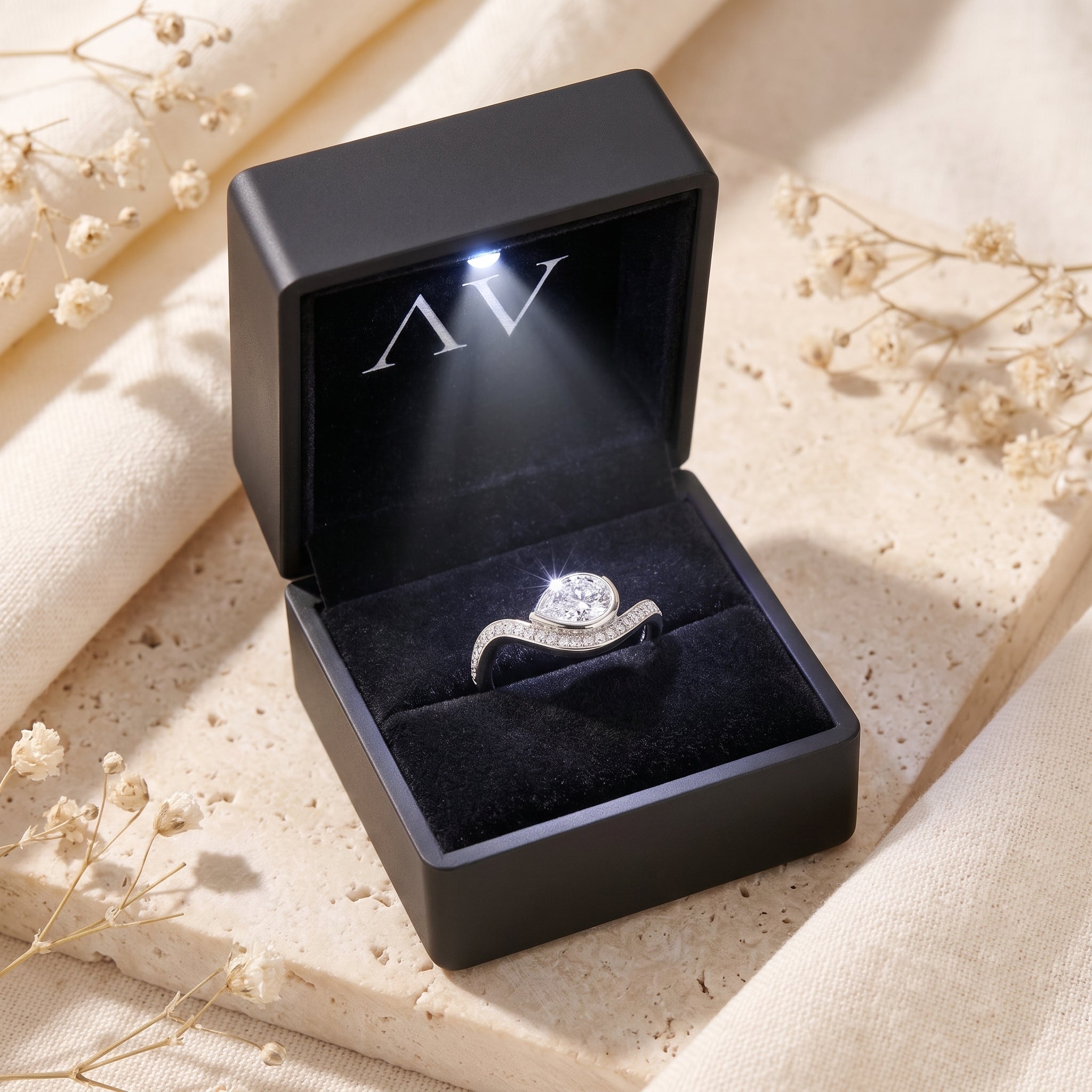 Silver pear moissanite ring in a black LED-lit gift box.
