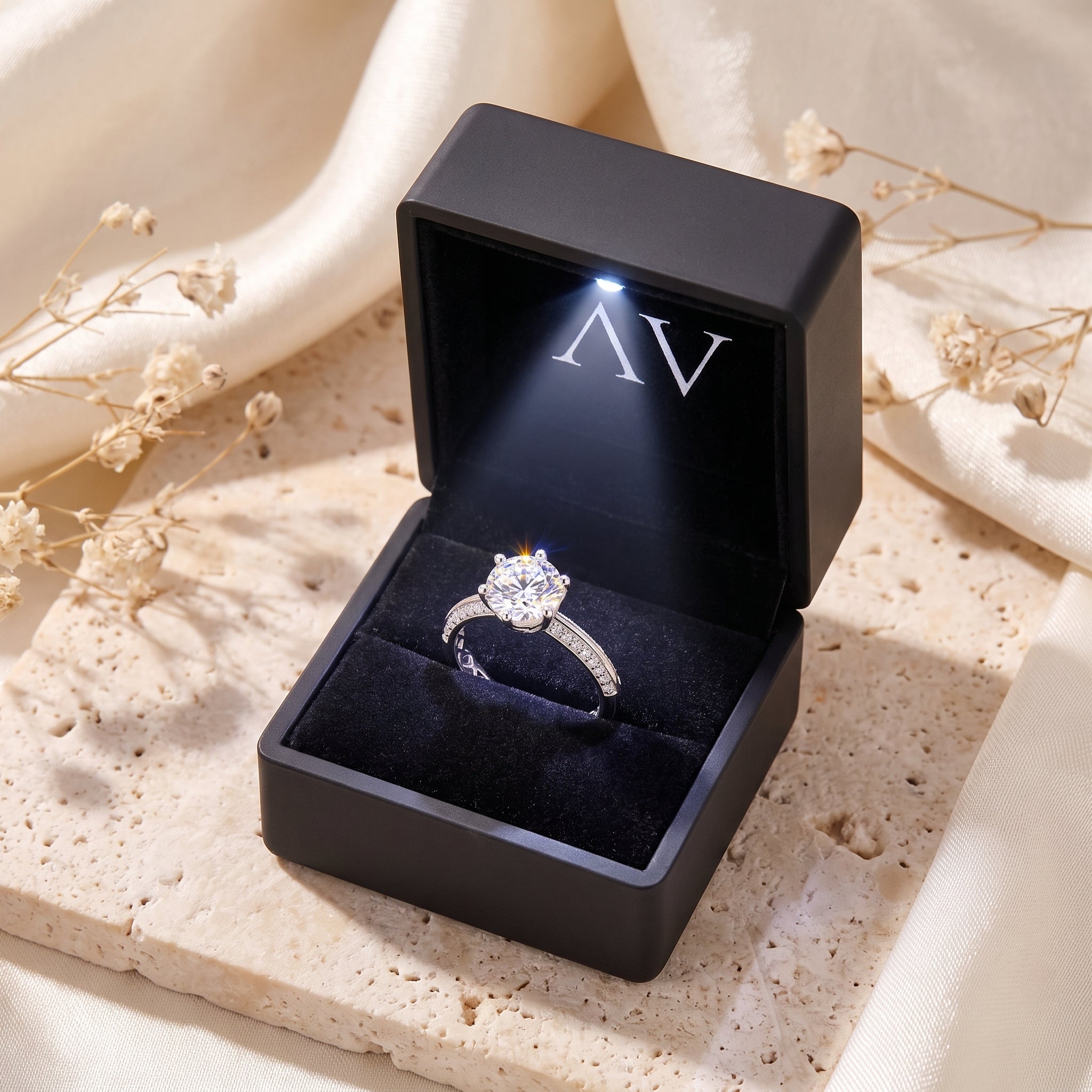 Silver solitaire ring inside a black LED-lit presentation box.