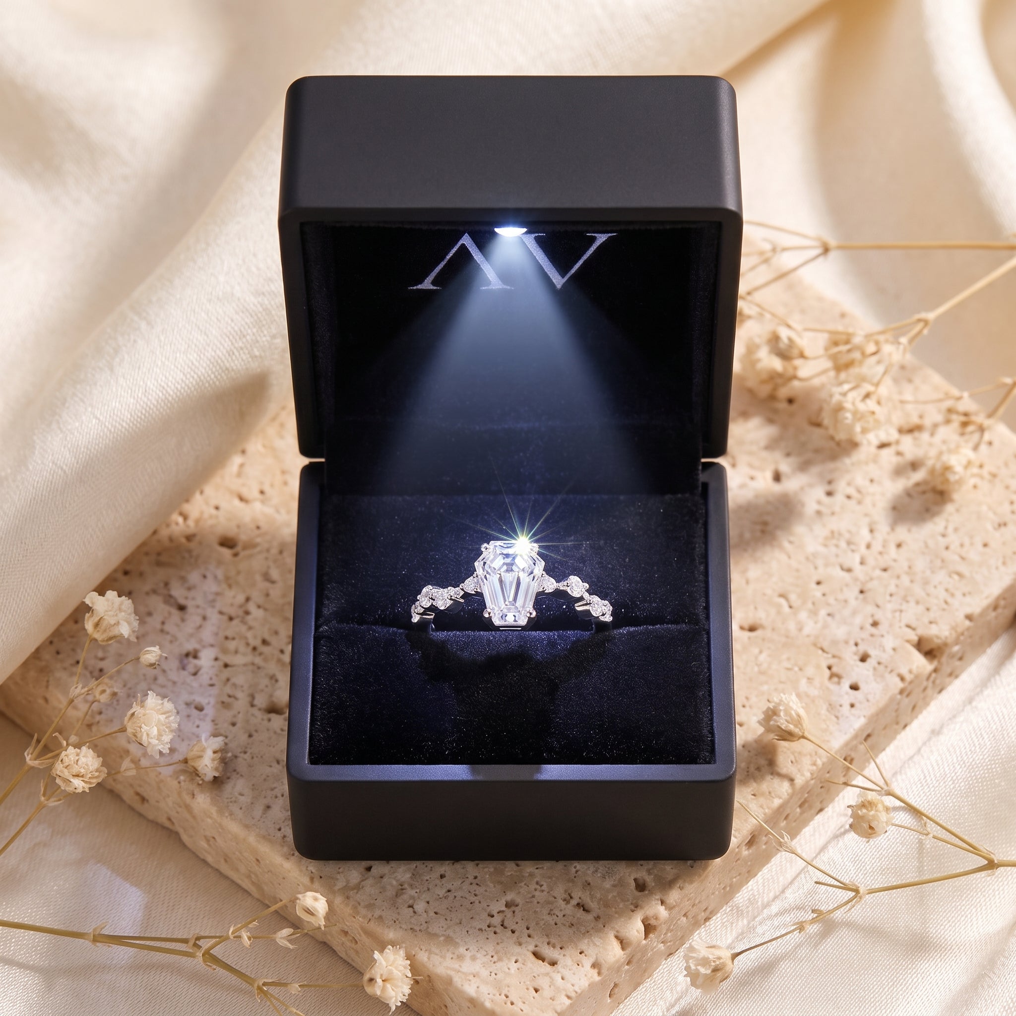 Silver Rosmerta coffin-cut ring inside a black LED-lit jewelry box, highlighting the stone's brilliance.