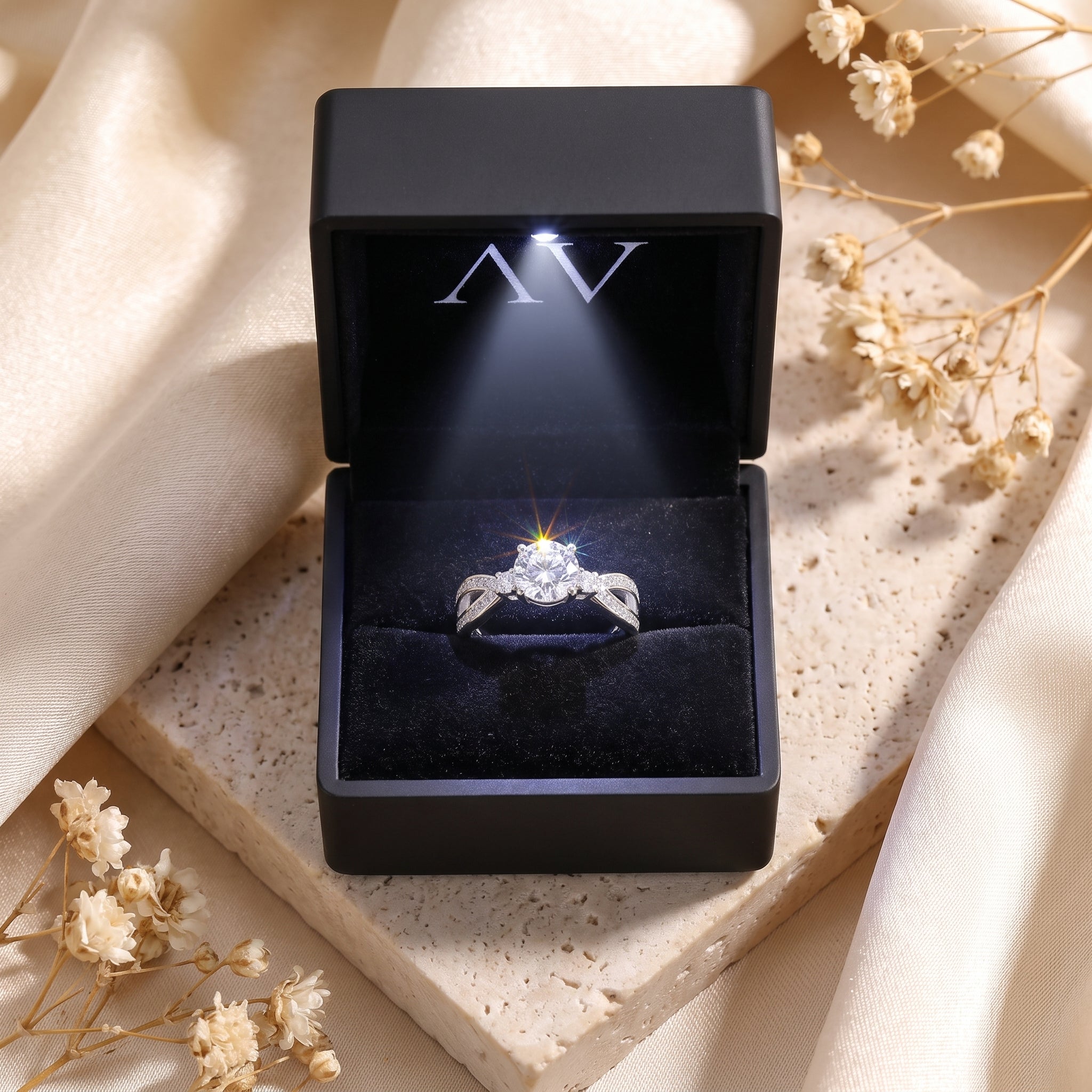 The Noeline sterling silver promise ring with a brilliant round stone inside a lighted black jewelry gift box.