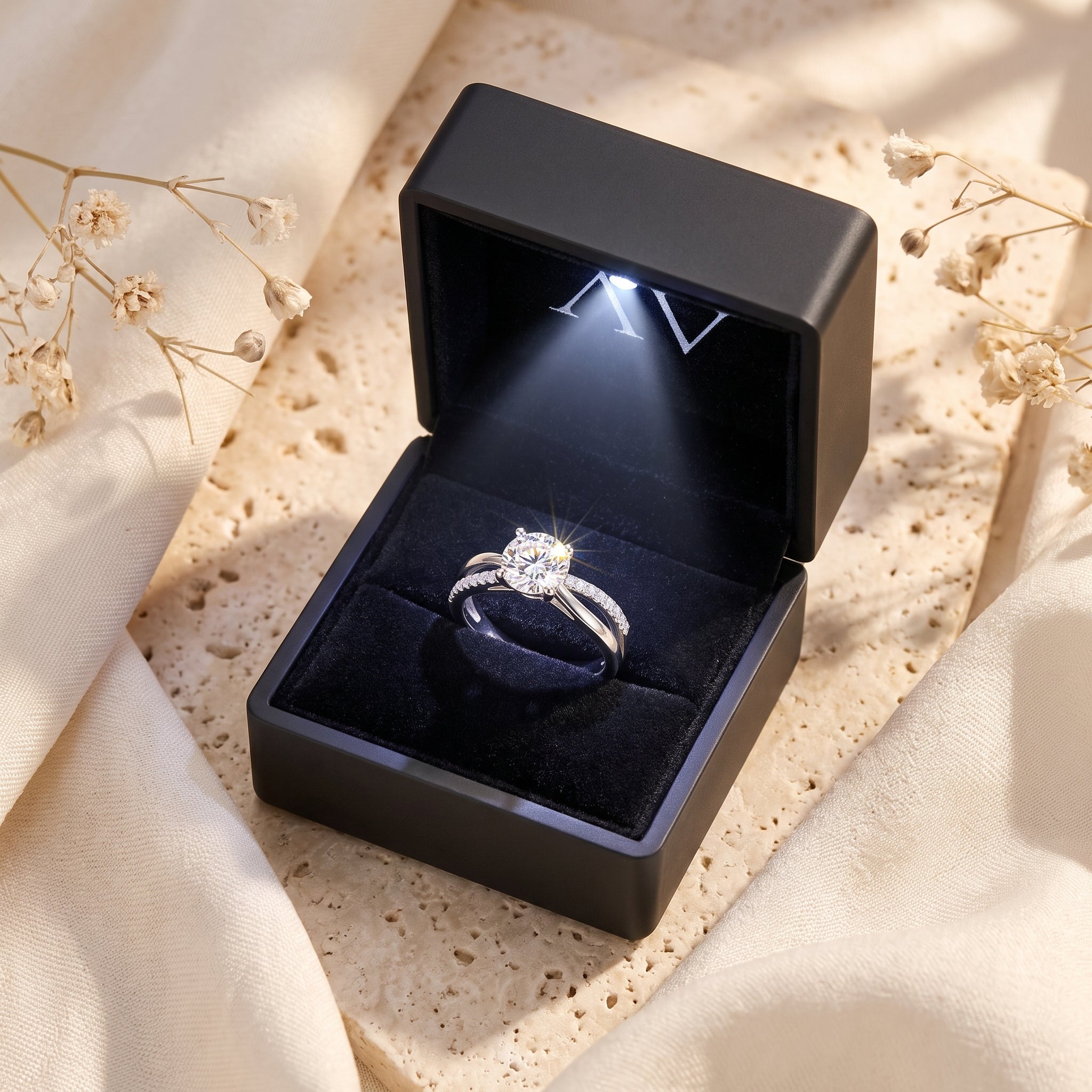 Sterling silver simulated April birthstone ring inside a black LED-lit jewelry gift box on a stone surface.