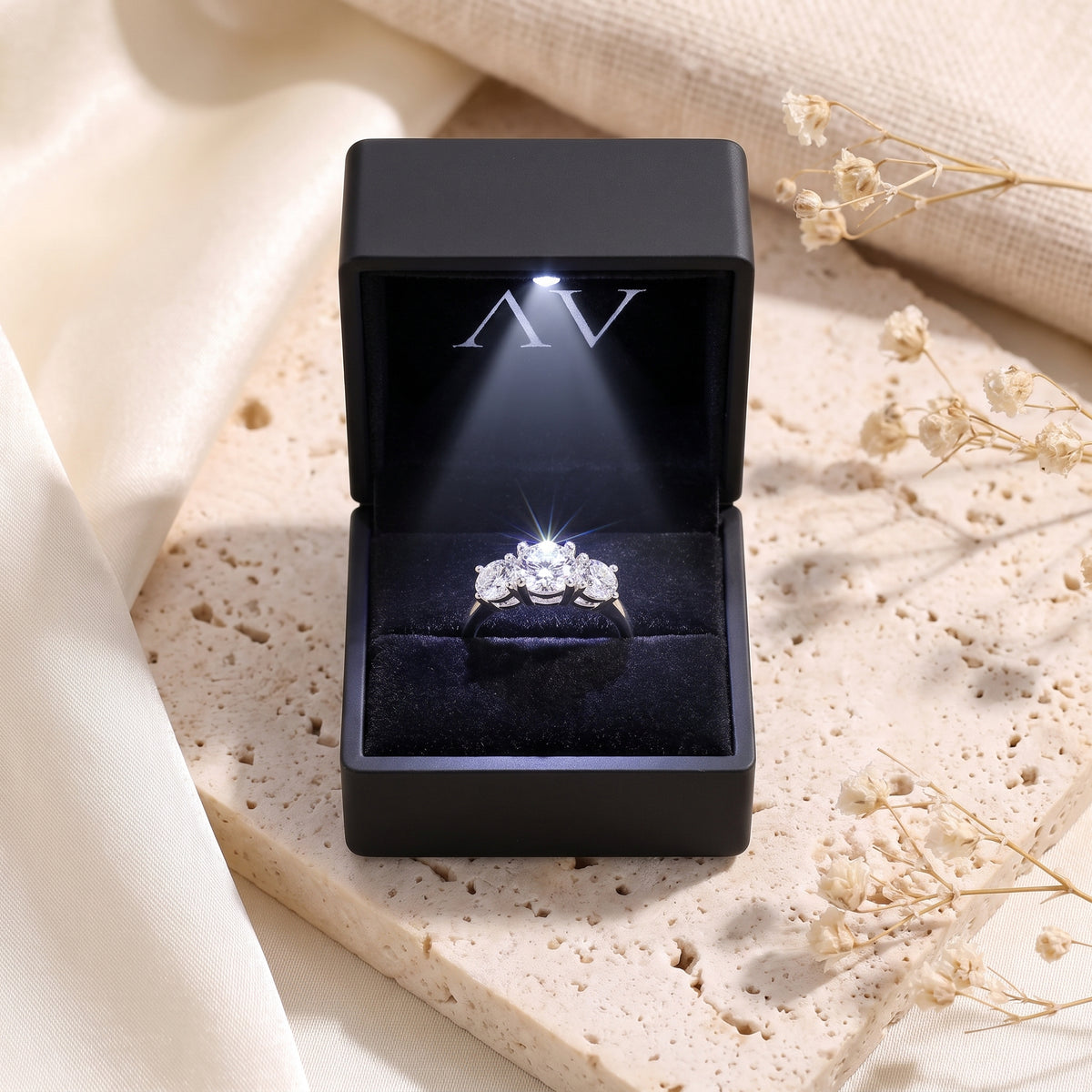 Three-stone simulated diamond ring in a lighted black gift box.