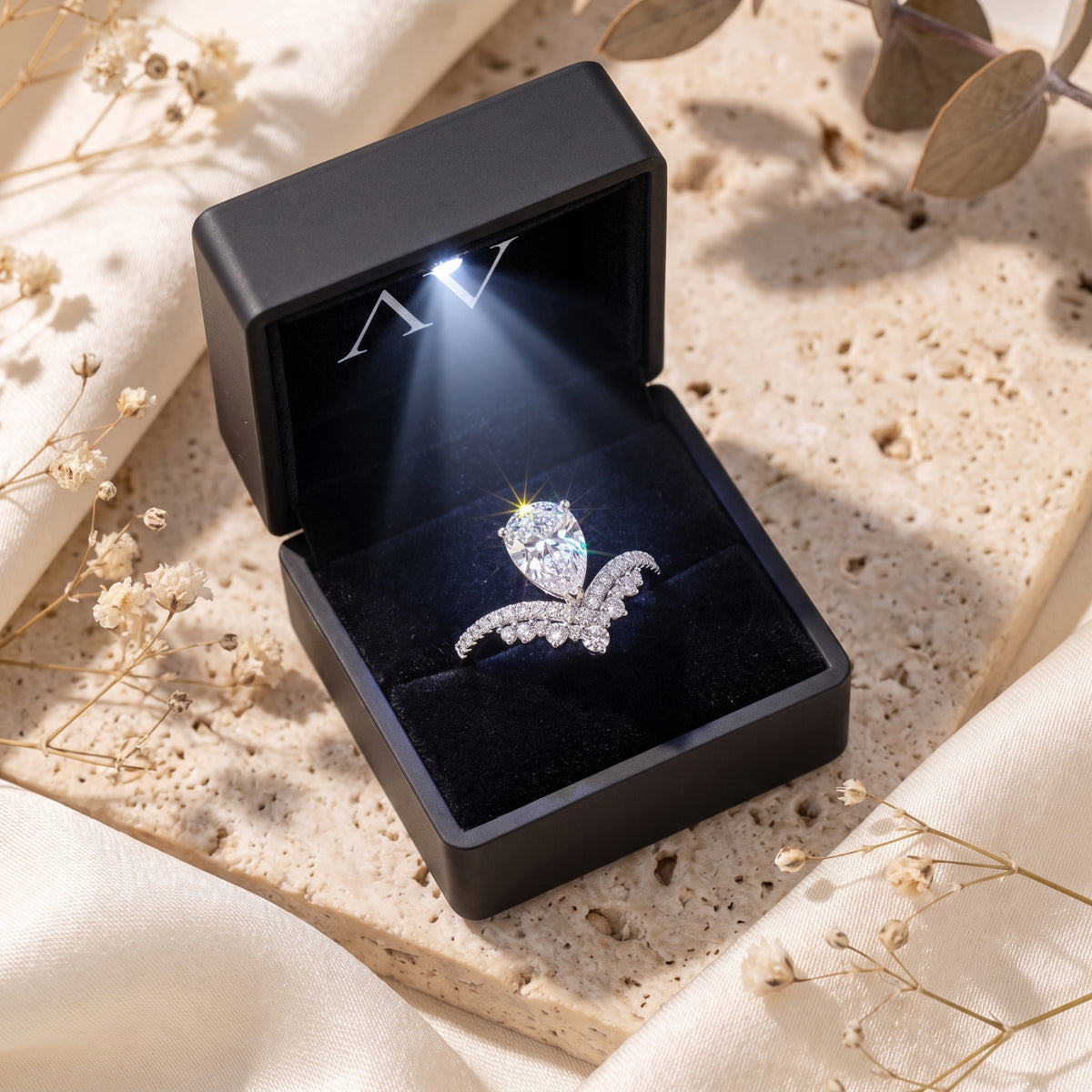 Silver pear-cut simulated diamond wishbone ring in a black lighted gift box.