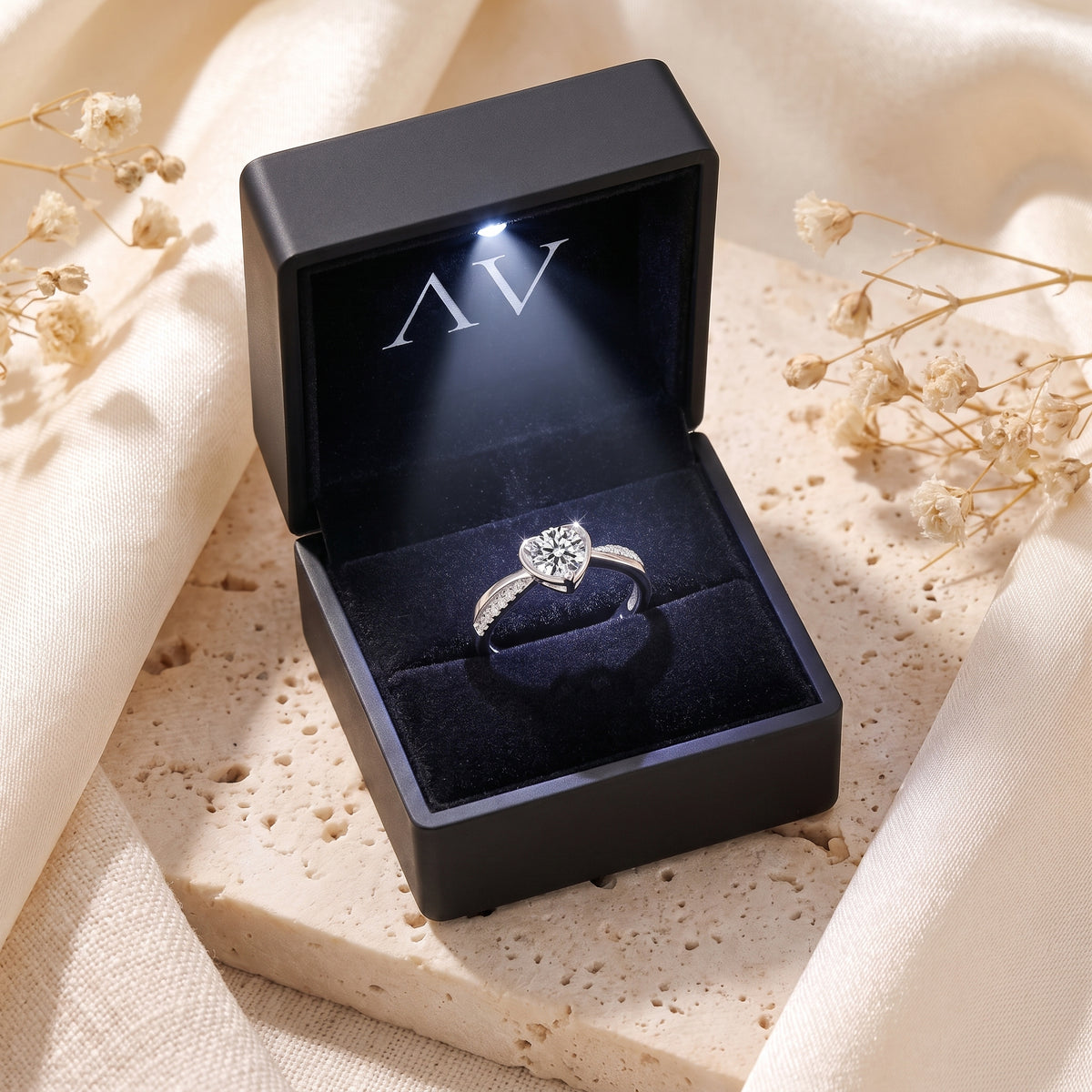 Sterling silver heart bypass ring inside a black LED-lit presentation box with branded AV logo.