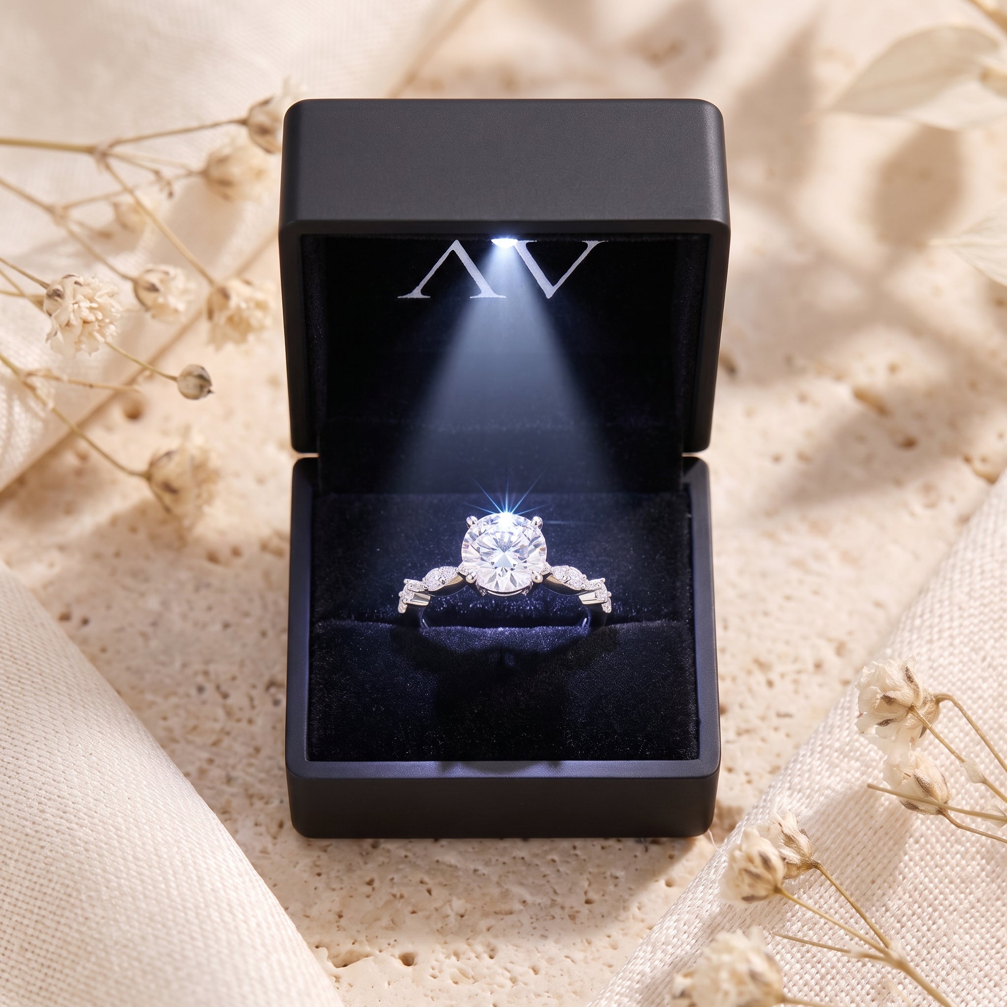 Round-cut simulated diamond solitaire ring in a lighted black velvet presentation box.