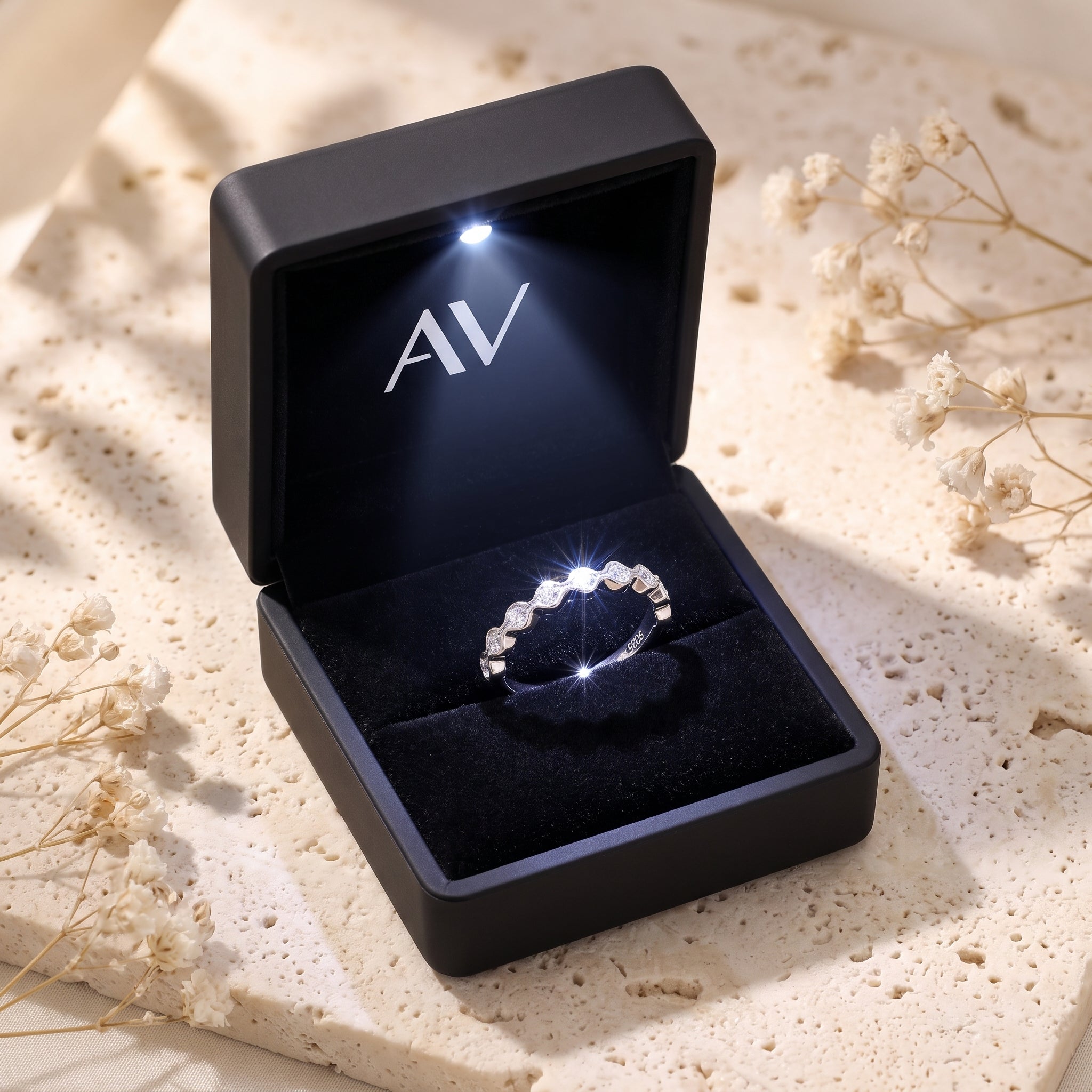 Wavy silver simulated diamond ring inside a black LED-lit jewelry gift box.