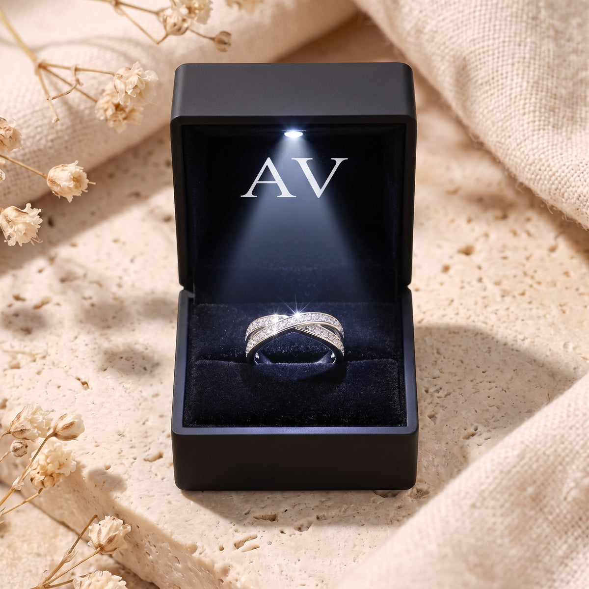 Silver crossover ring inside a black gift box with an integrated LED light.