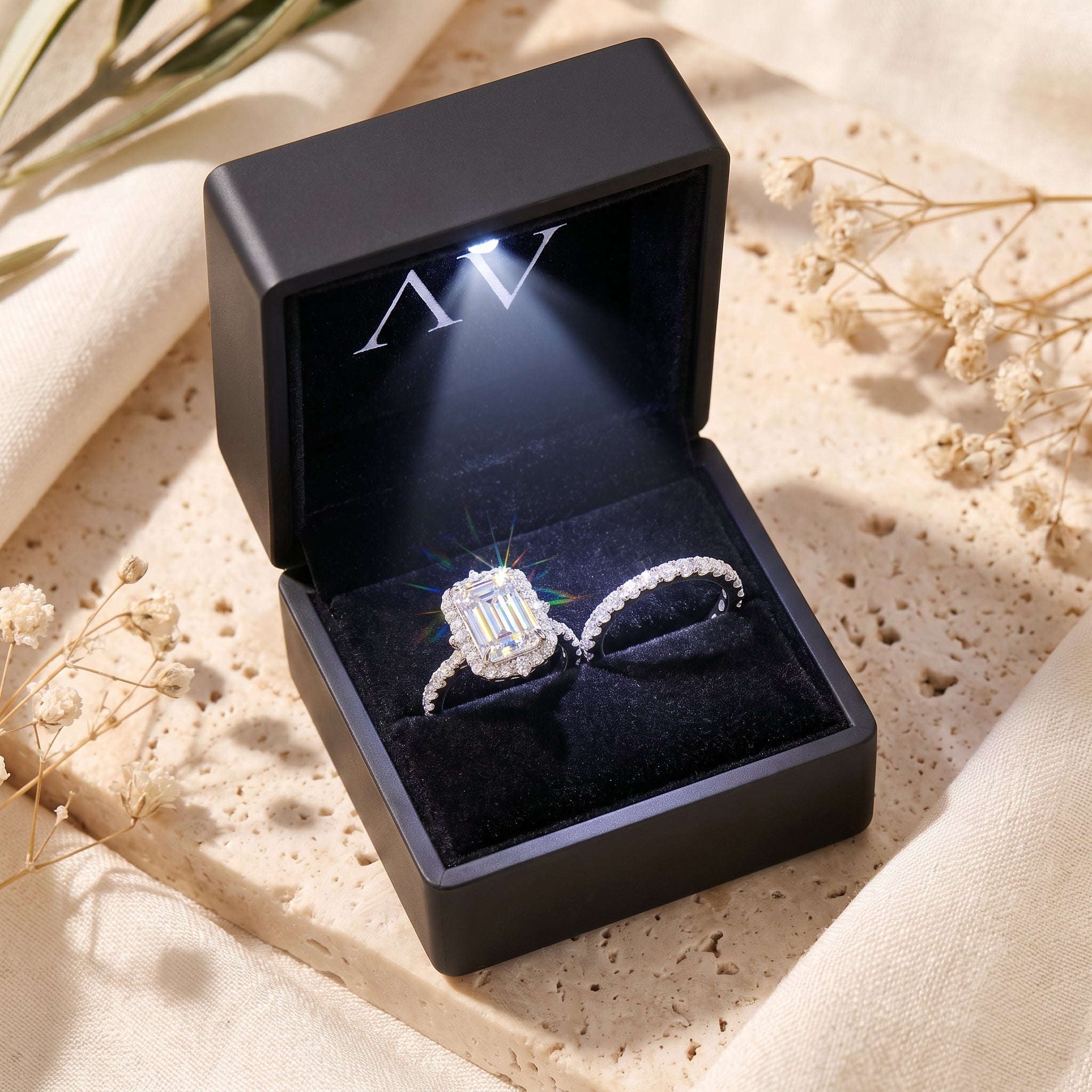 Silver emerald-cut halo ring set presented in a black LED-lit jewelry gift box.
