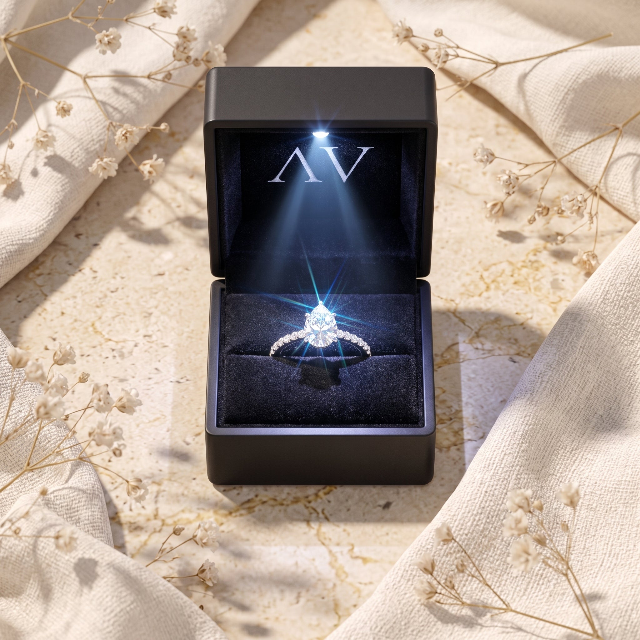 Pear cut simulated diamond ring inside a black LED-lit presentation box.