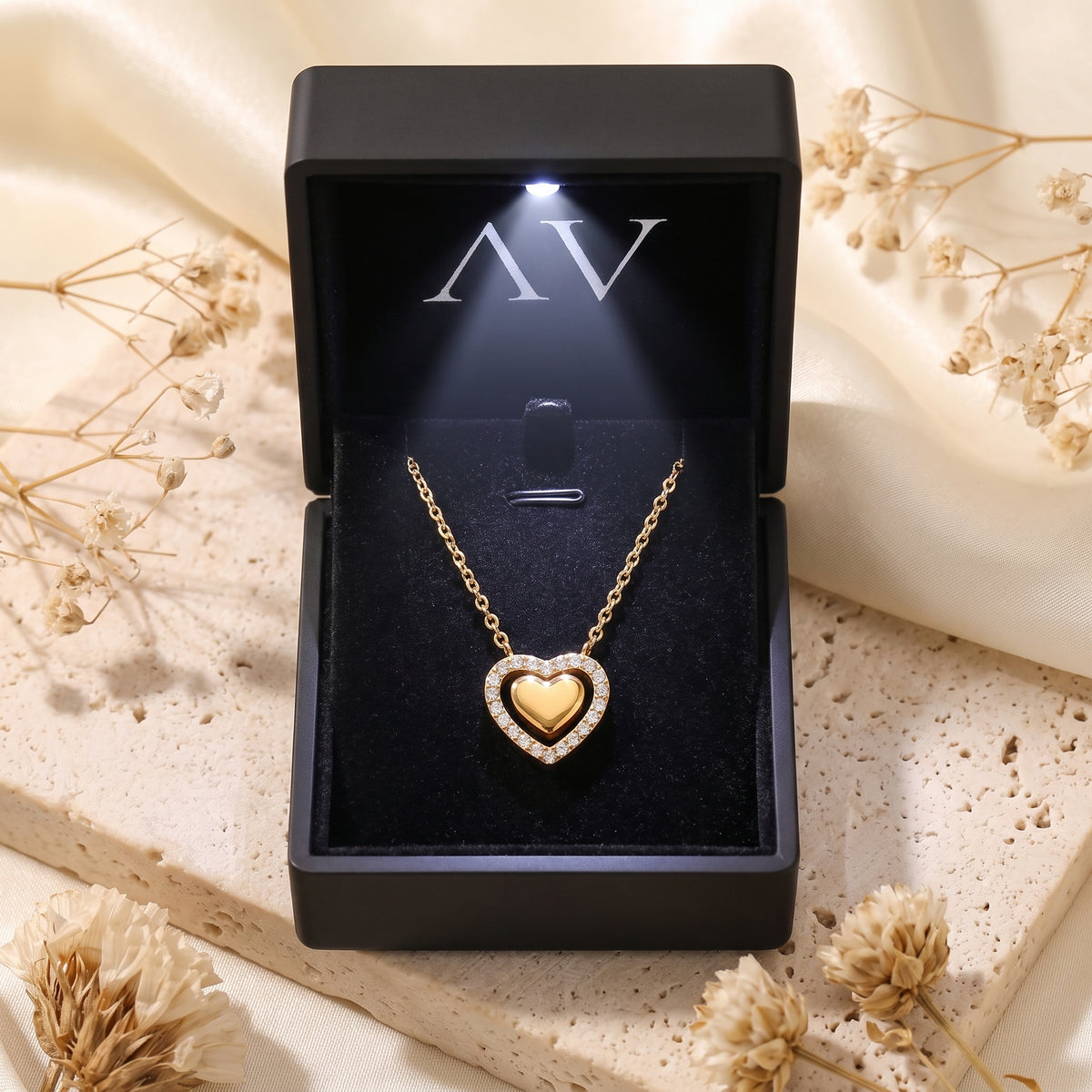 Gold double heart pendant necklace presented in a black LED-lit jewelry gift box on a lifestyle background.
