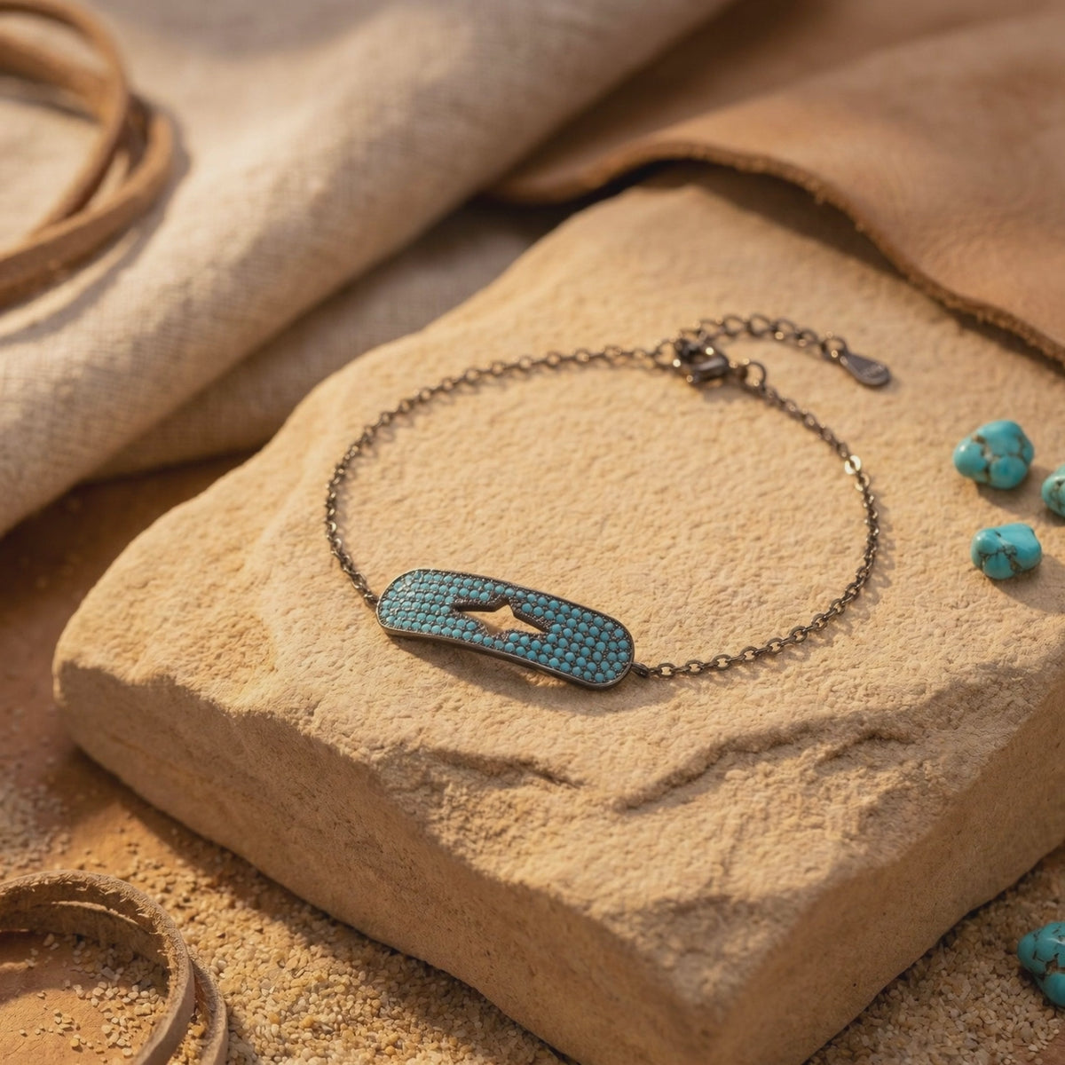 Bracelet displayed flat on a rustic tan stone surface, showing its turquoise station, star-shaped cutout, chain, and clasp.