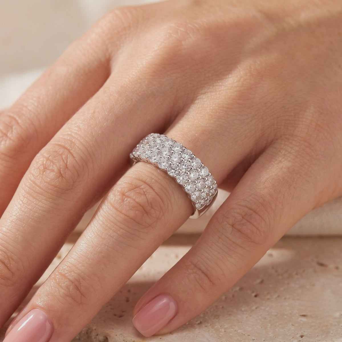 Wide silver multi-row pavé ring with sparkling round stones, worn on a hand.