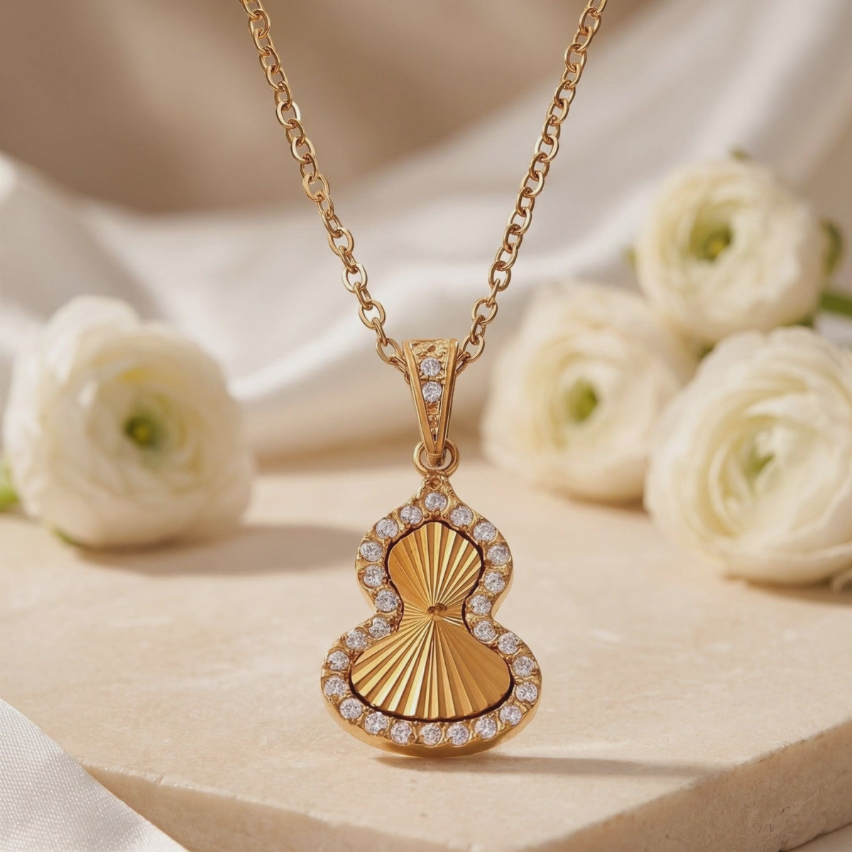 Close-up of the gold-tone Sorsha pendant displaying its sunburst texture and cubic zirconia halo.