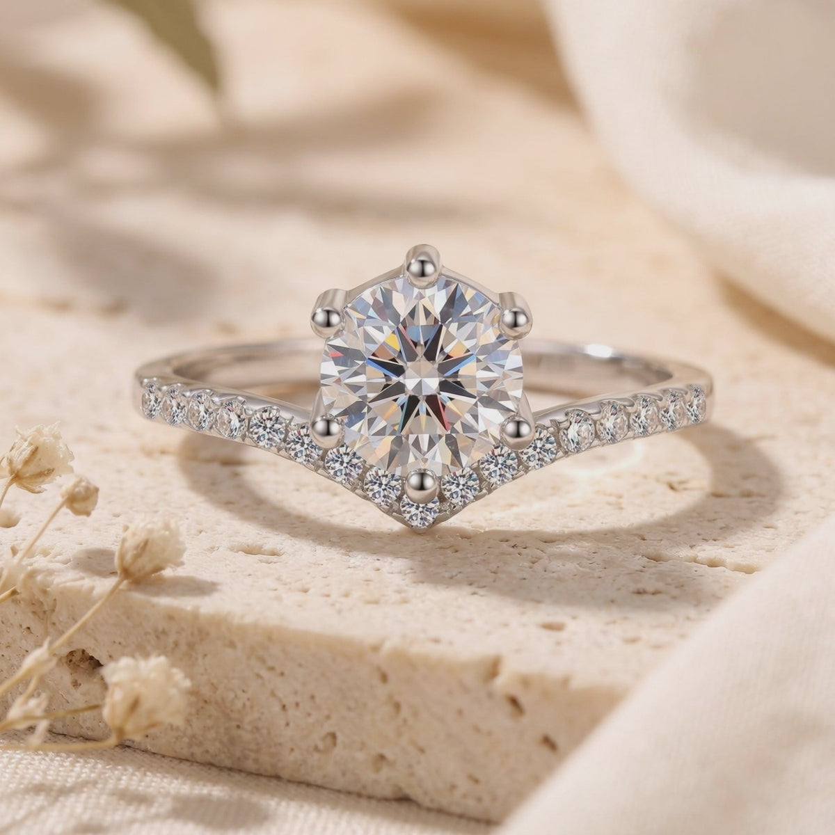 Close-up frontal view of a silver chevron solitaire ring resting on a textured stone surface.