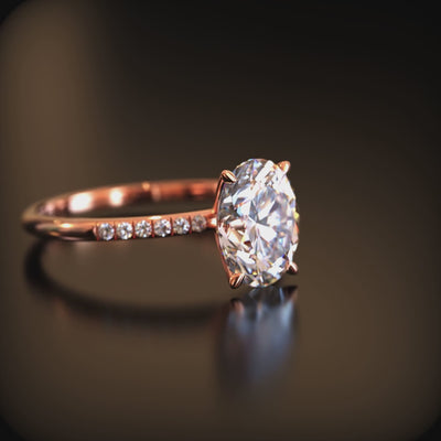 An oval moissanite ring in solid gold with a pavé band.