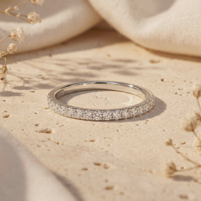 Video preview of a silver moissanite pave band resting on a beige textured surface.