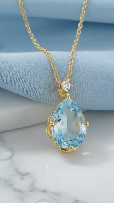 Solid gold necklace with simulated aquamarine teardrop pendant.