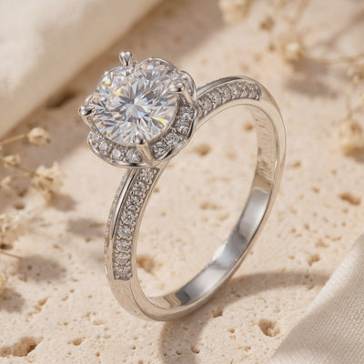 Close-up of the silver-toned Fleur Bloom Ring upright, showing its round stone, six-prong petal halo, and pavé band.