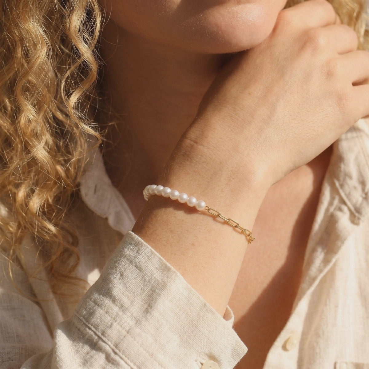 Video preview of a model wearing the half-pearl, half-gold chain bracelet on her wrist.