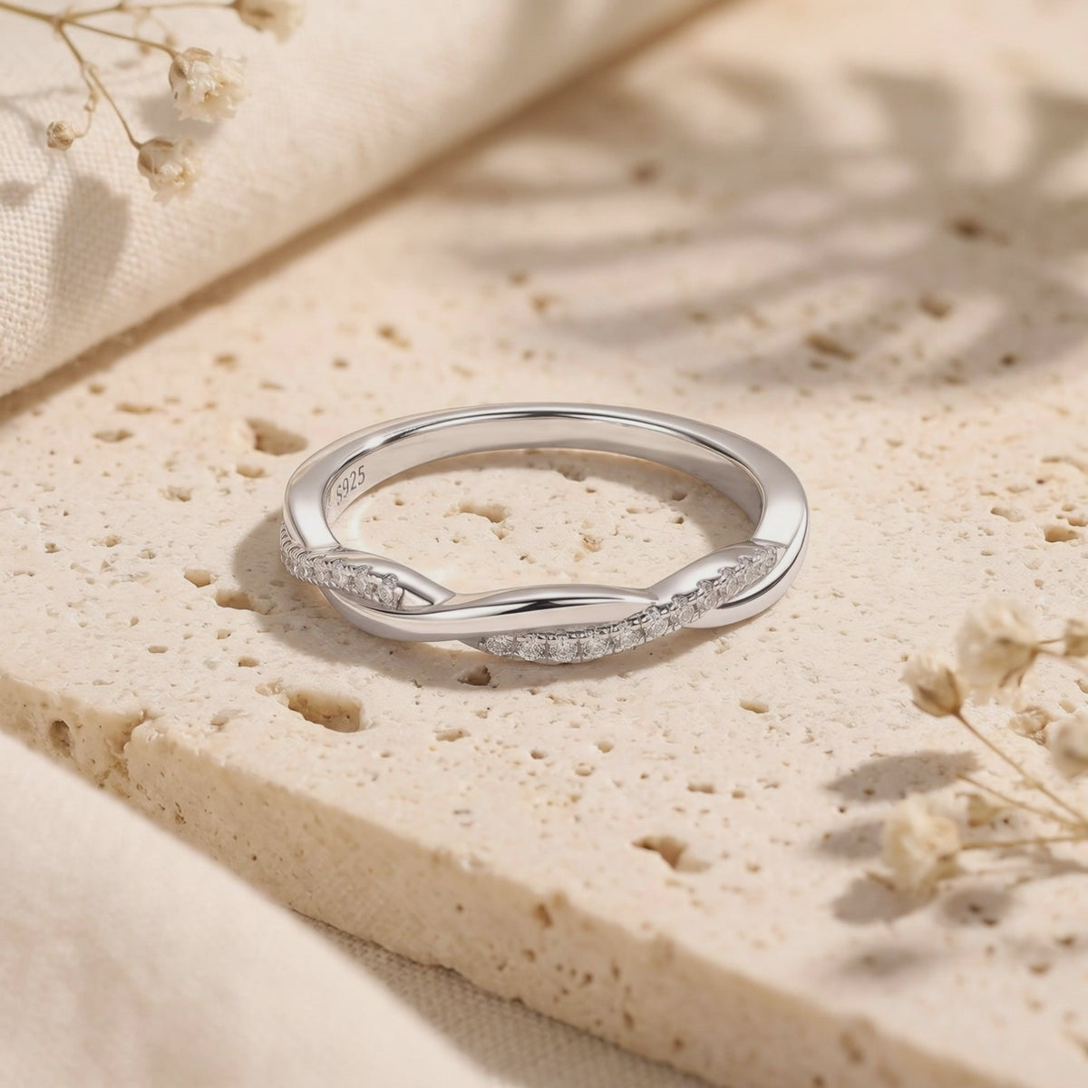 Silver twisted band ring resting on a textured stone slab, with the S925 stamp visible inside the band.