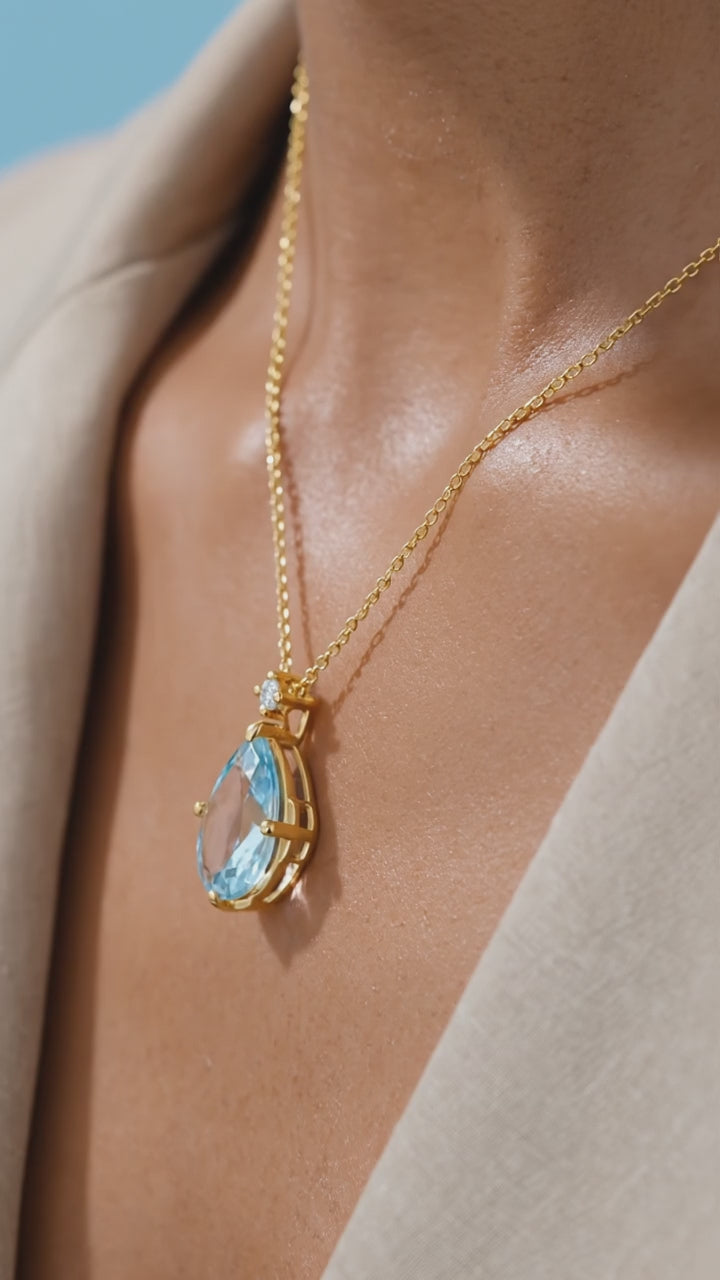 Solid gold necklace with simulated aquamarine teardrop pendant.