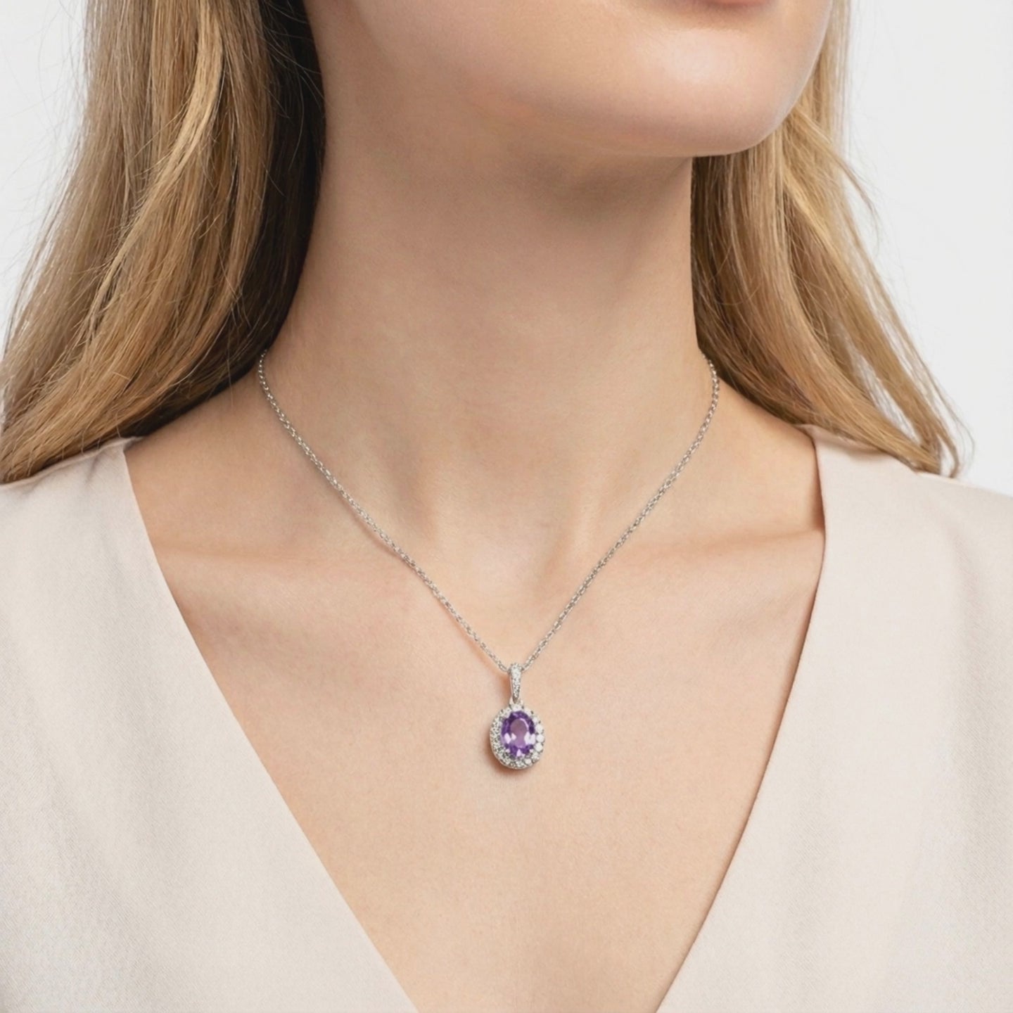 A solid gold necklace with an oval simulated amethyst halo pendant.