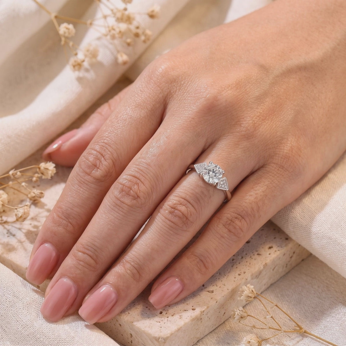 Silver Trinity Ring with a round clear center stone and triangular pavé accents worn on a hand.
