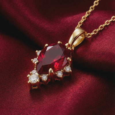 A solid gold necklace with a pear cut simulated ruby.