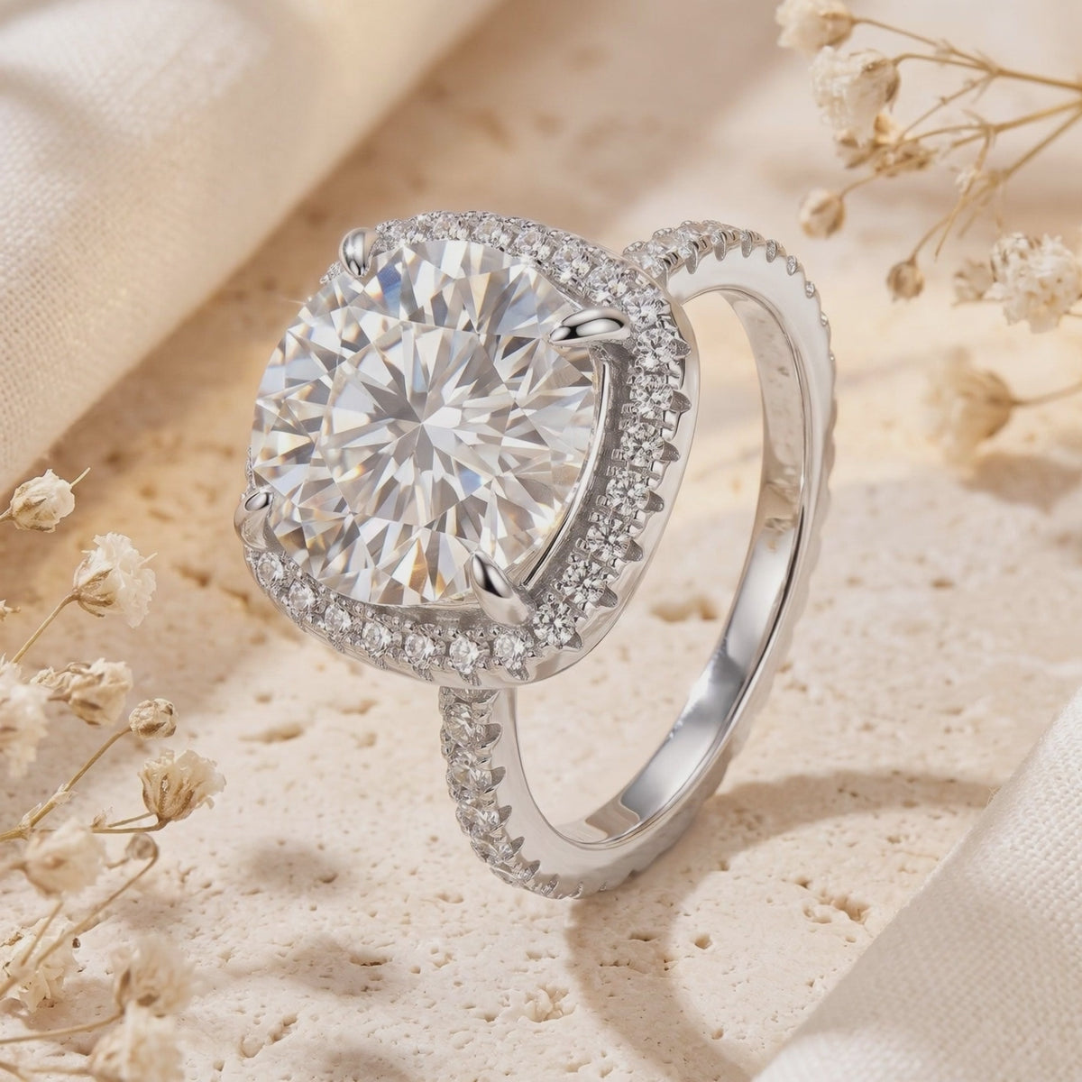 Angled view of a silver ring with a round center stone surrounded by a cushion pave halo and pave band.