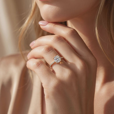 Cushion-cut pavé solitaire ring worn on a hand held near the wearer’s chin.