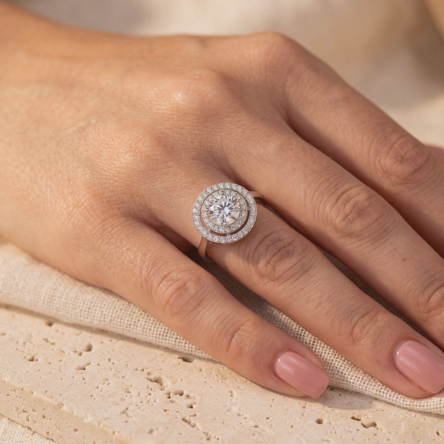 On-hand view of the silver double halo solitaire ring with a round clear center stone and dual accent halos.