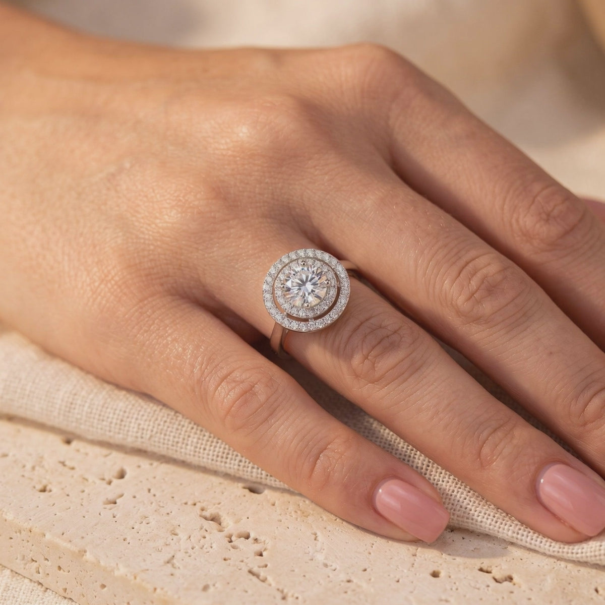 On-hand view of the silver double halo solitaire ring with a round clear center stone and dual accent halos.