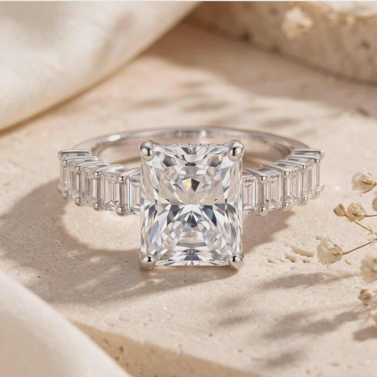 Close-up of the silver Ismerie ring resting on a pale textured surface, showing its radiant-cut center and side accents.
