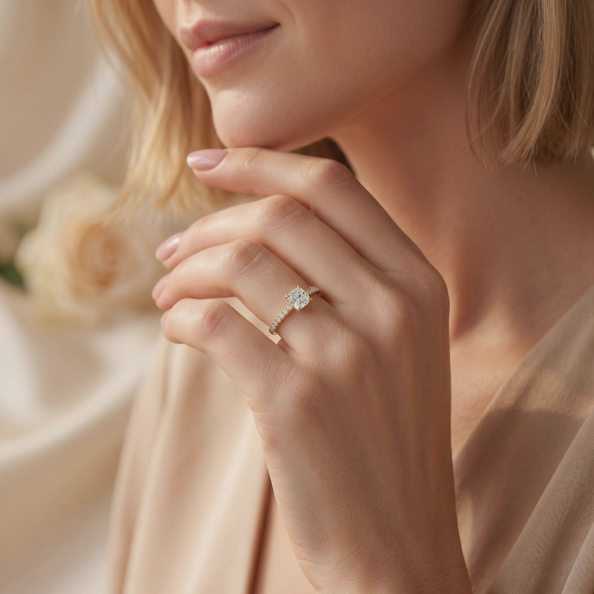 Woman wearing the cushion-cut pavé solitaire ring with her hand resting near her chin.