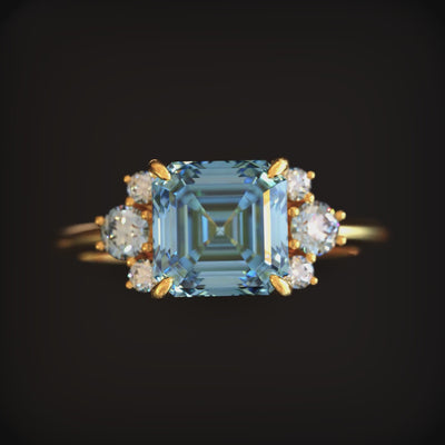 A solid gold ring with a blue moissanite.
