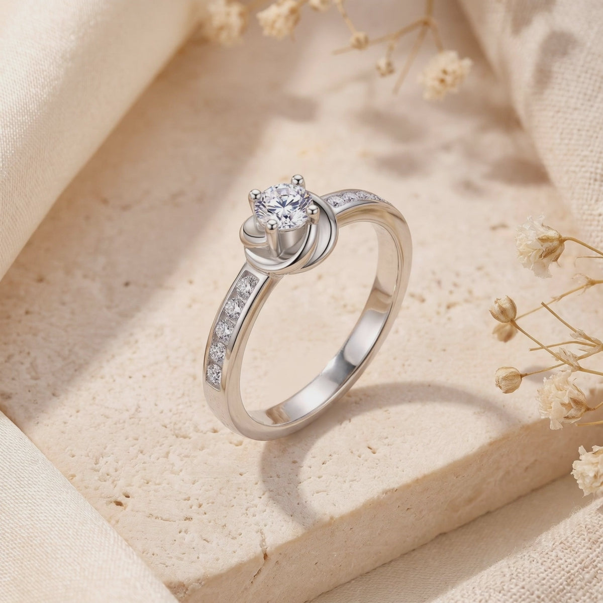 Silver Melisande bypass ring shown upright at an angle, with a round prong-set center stone and accent stones.