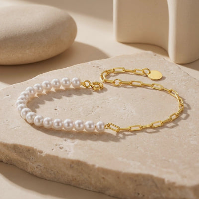 Video preview of the half-pearl and gold link chain bracelet laid out on a beige stone slab.
