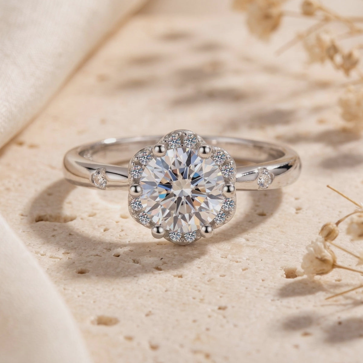 Close-up of the silver flower halo ring with a round clear stone resting on a textured stone surface.