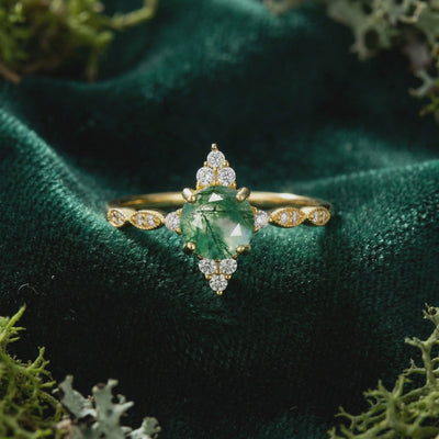 Solid gold ring with a marquise natural moss agate stone in a sunburst setting.