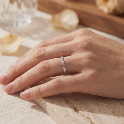 Silver twisted band ring with pavé-set stones worn on a finger in a close-up hand view.
