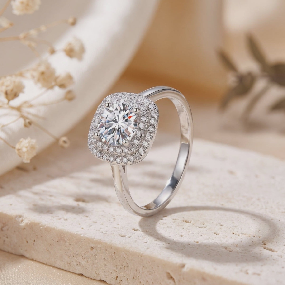 Silver ring with a round central stone and double cushion halo set on a textured stone block.