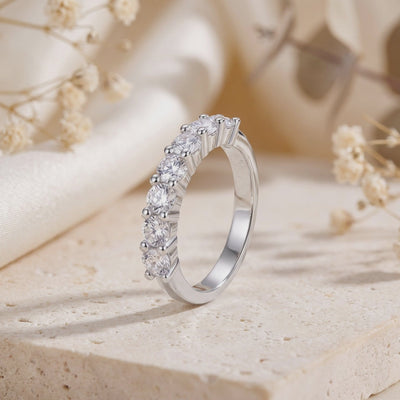 Preview frame of a silver band with seven round clear stones standing upright on a beige stone surface.