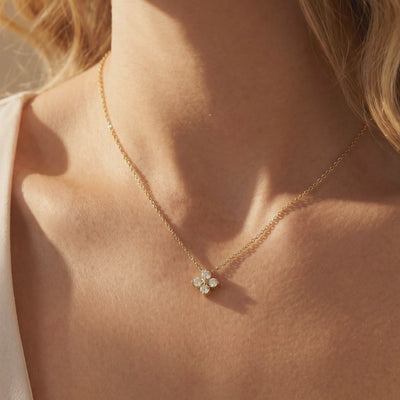 Woman wearing a gold-tone four-stone floral moissanite pendant necklace on her collarbone.