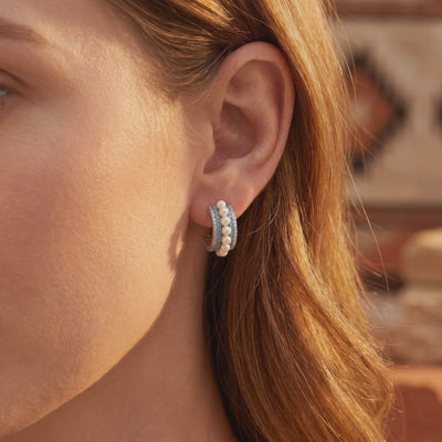 Model wearing a silver C-hoop earring with rows of white pearls, blue turquoise, and clear accents.