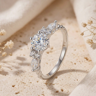 Close-up of the silver vintage-style Carlotta ring with round and marquise stones standing on a textured surface.