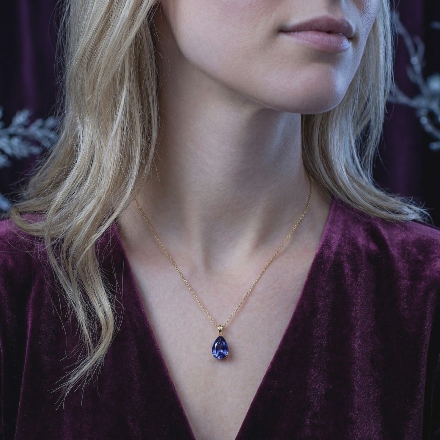 A solid gold necklace with a pear-cut simulated tanzanite pendant.